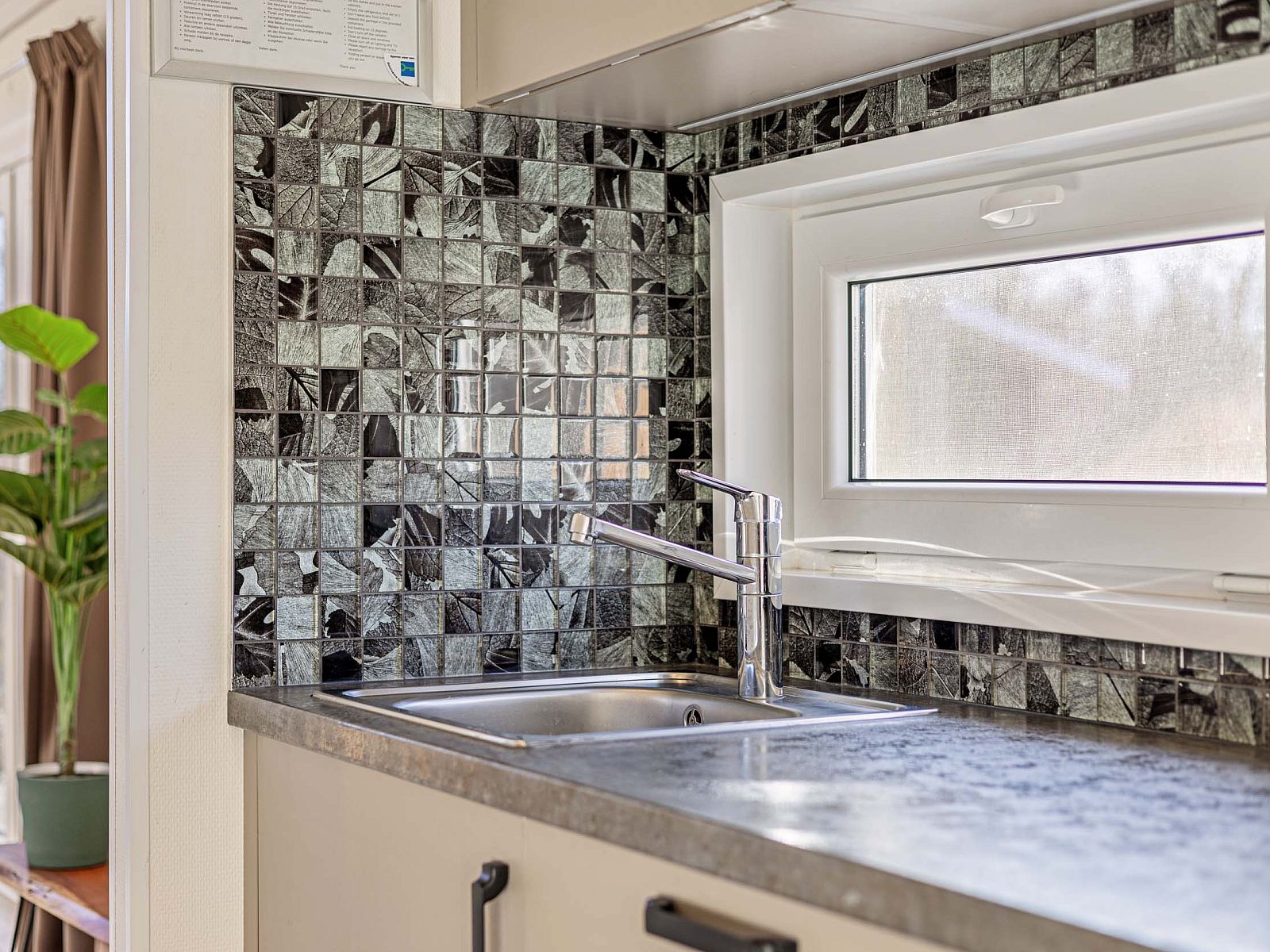 Detail of kitchen in Lindenhoeve 2.0 vacation home, Lichtenvoorde, with modern countertop and window in the Achterhoek.