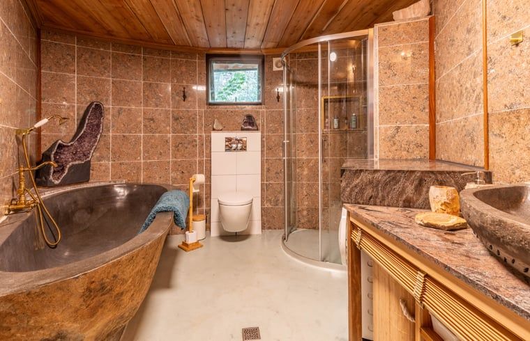 Luxe bad in Vakantiehuis in Neede, Achterhoek, met unieke stenen afwerking en sfeervolle verlichting.
