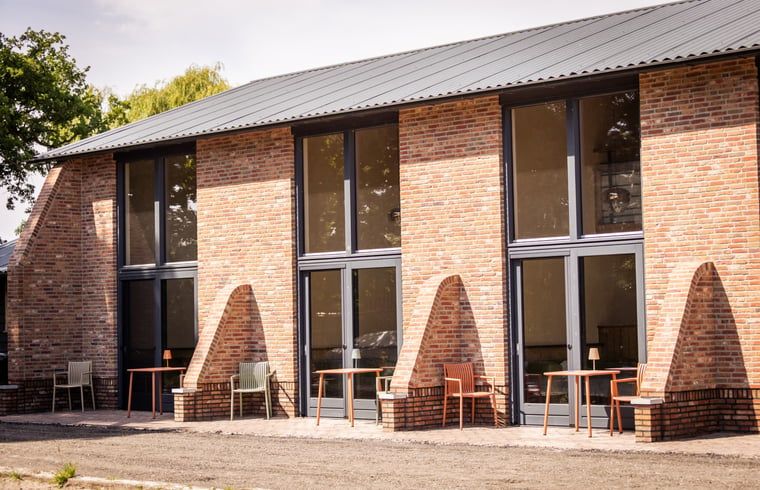 Buitenzijde van Vakantiehuisje in Neede, Achterhoek, met uitnodigende terrassen voor ontspanning.