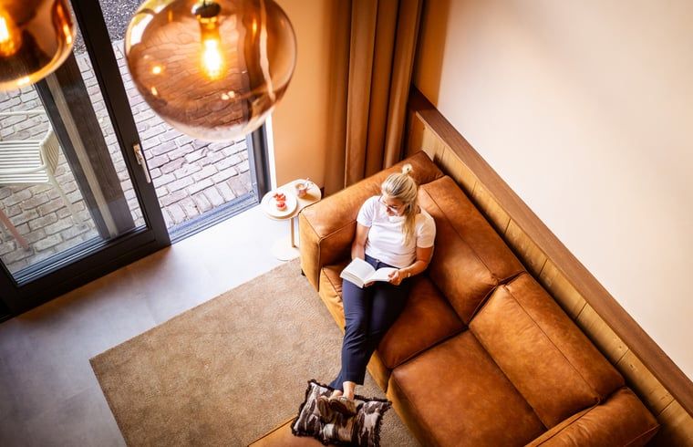 Ontspannen lezen op bank in Vakantiehuisje in Neede, Achterhoek, met warme verlichting.