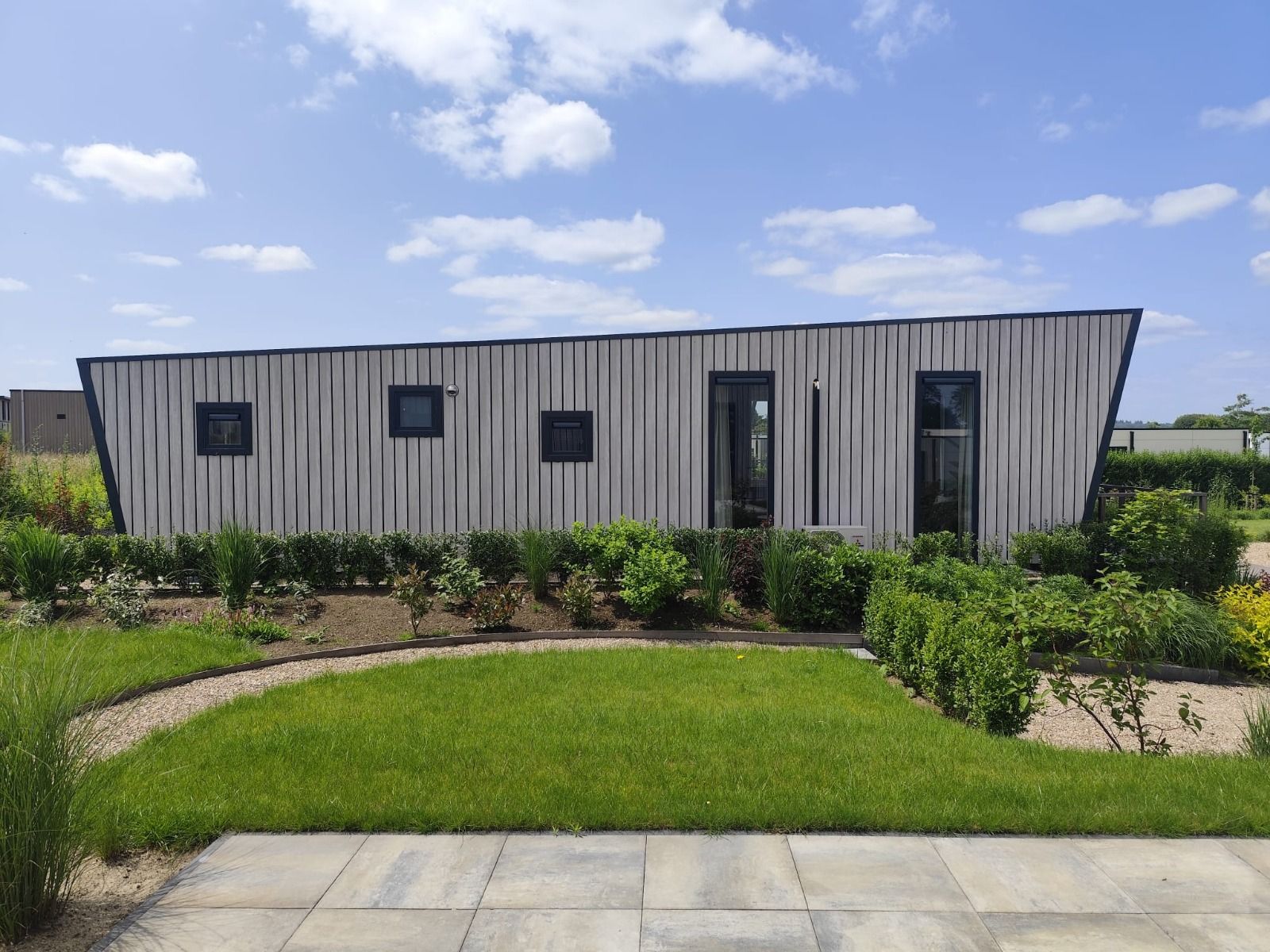 Detached house in Olburgen, Achterhoek: modern vacation home with green garden and clear blue sky in Gelderland.