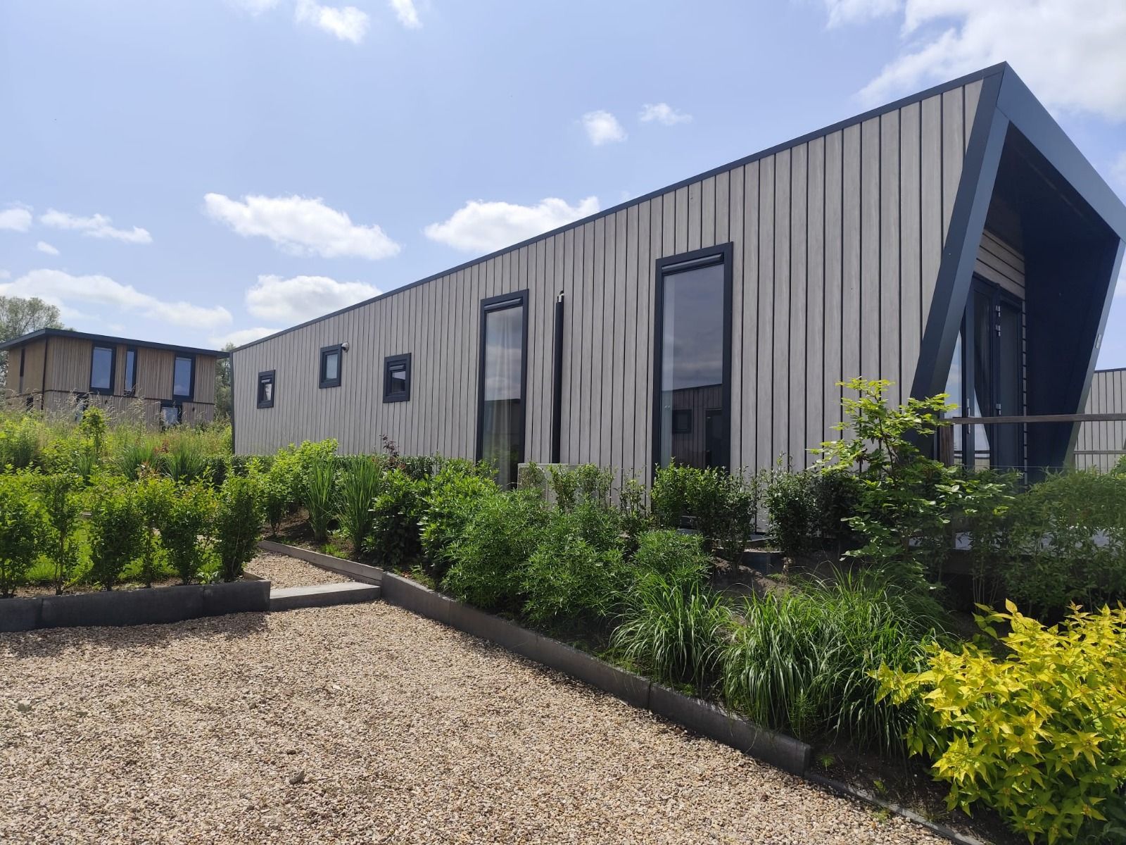 Detached house in Olburgen, Achterhoek, Gelderland, surrounded by green garden and blue sky, ideal vacation home for peace seekers.