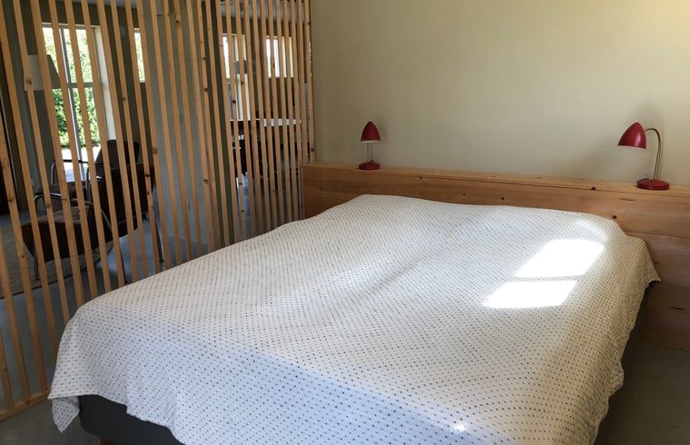 Cottage in Almen, Ferienhaus in Achterhoek, Gelderland. Schlafzimmer mit Holzbettgestell und viel natuerlichem Licht.