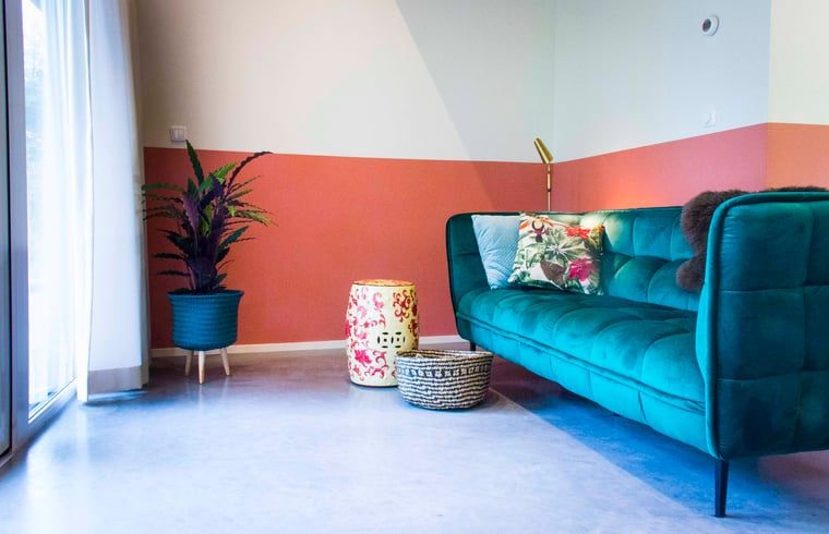 Stijlvolle woonkamer met groene bank in Vakantiehuisje in Joppe, Achterhoek, Gelderland.