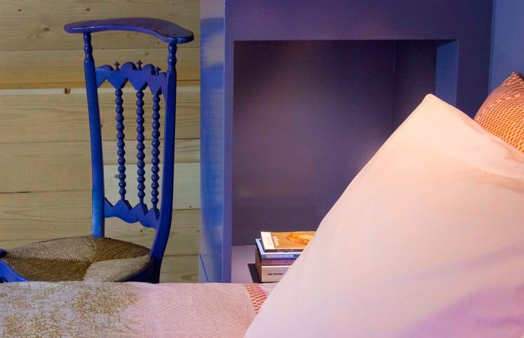 Detail van slaapkamer met blauwe stoel in Vakantiehuisje in Joppe, Achterhoek, Gelderland.