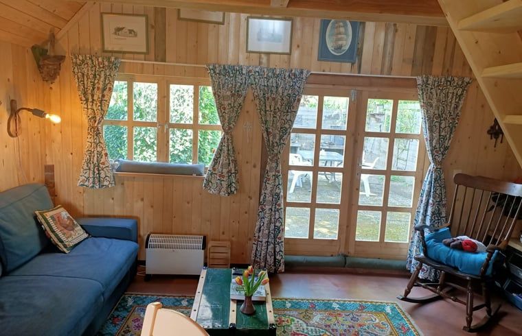 Gemuetlicher Innenbereich des Ferienhauses in Winterswijk Corle, gelegen in Achterhoek, Gelderland, mit Holzinterieur und Blick auf die Terrasse.