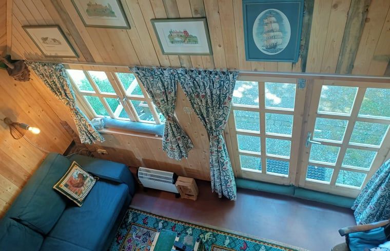 Gemuetliches Wohnzimmer im Ferienhaus in Winterswijk Corle, Achterhoek, Gelderland mit Holzinterieur und viel natuerlichem Licht.