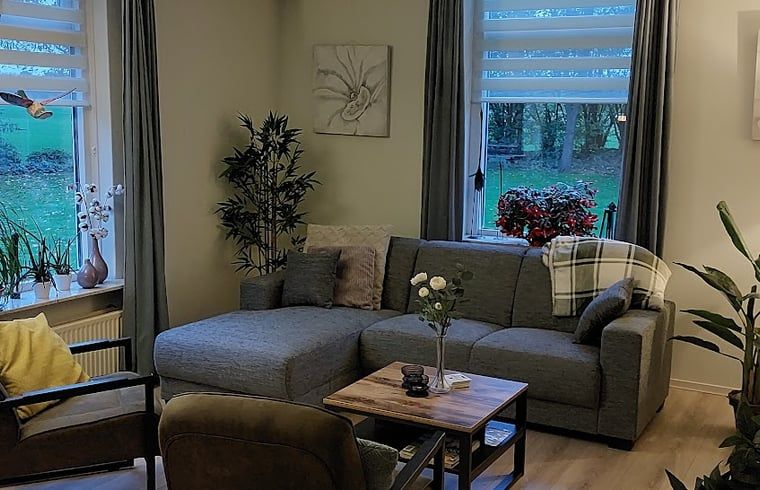 Cozy living room in Holiday Home in Winterswijk Corle, Achterhoek, with comfortable seating area and views of the green nature of Gelderland.