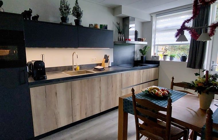 Dining area in the kitchen of Holiday Home in Winterswijk Corle, overlooking the garden in Achterhoek, Gelderland.