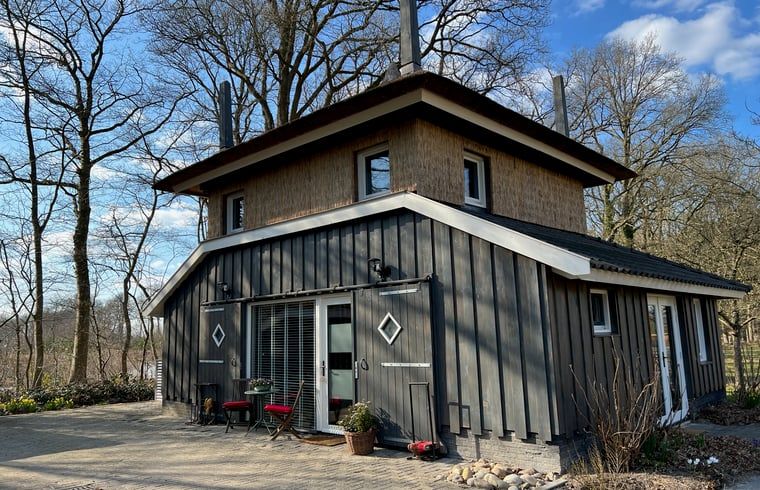 Charmant exterieur van Huisje in Empe, vakantieverblijf in Gelderland, omgeven door bomen.