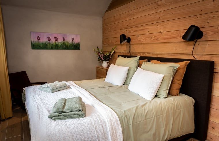 Sfeervolle slaapkamer in Huisje in Empe, vakantieverblijf Gelderland, met houten wanden en comfortabel bed.