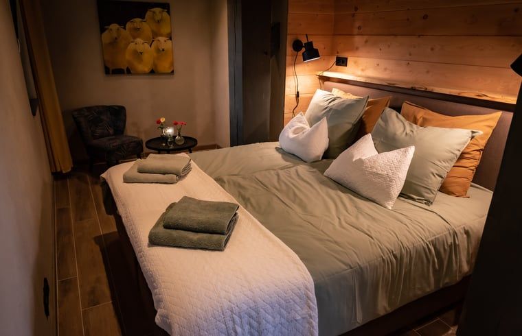 Knusse slaapkamer in Huisje in Empe, vakantiehuis Gelderse vallei, met warme inrichting en kunst aan de muur.