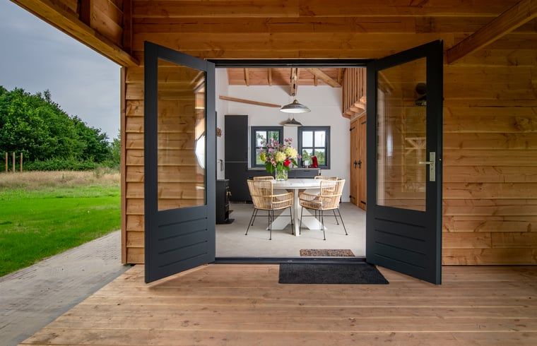 Gezellige binnenruimte van Vakantiehuis in Empe, Gelderse vallei, met open deuren naar terras en uitzicht op de natuur.