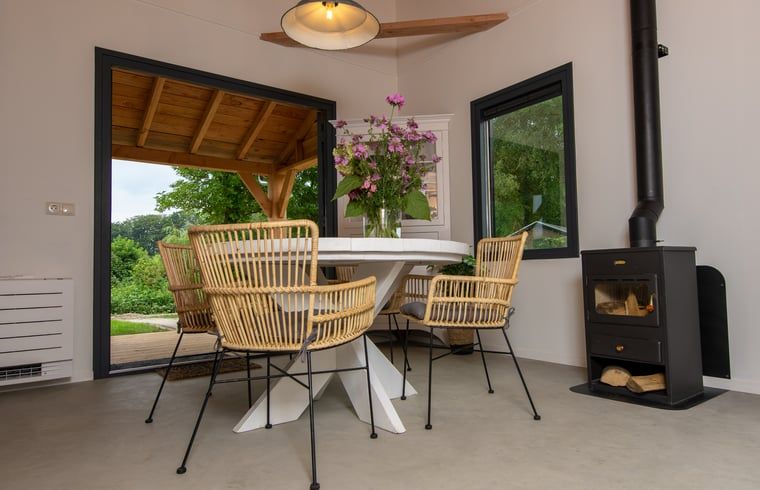 Gezellige eetruimte van Vakantiehuis in Empe, Gelderse vallei, met uitzicht op groene natuur en sfeervolle houtkachel.