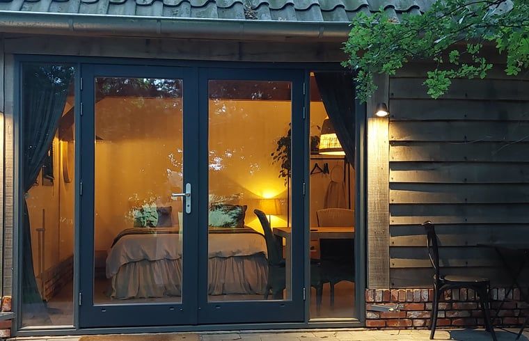 Gezellige slaapkamer van Huisje in Tonden, vakantiehuis in de Gelderse vallei, met warme verlichting en uitzicht op de natuur.