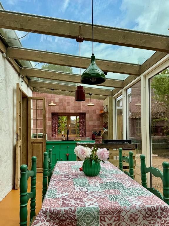 Heller Essbereich im In de Aap - Apartments & Guesthouse, Bergen, Nordholland, mit Glasdach und farbenfrohem Dekor.