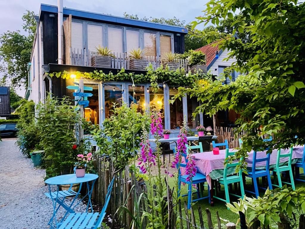 Charmanter Aussenbereich von In de Aap - Apartments & Guesthouse in Bergen, Nordholland, mit bunten Stuehlen und bluehenden Pflanzen.