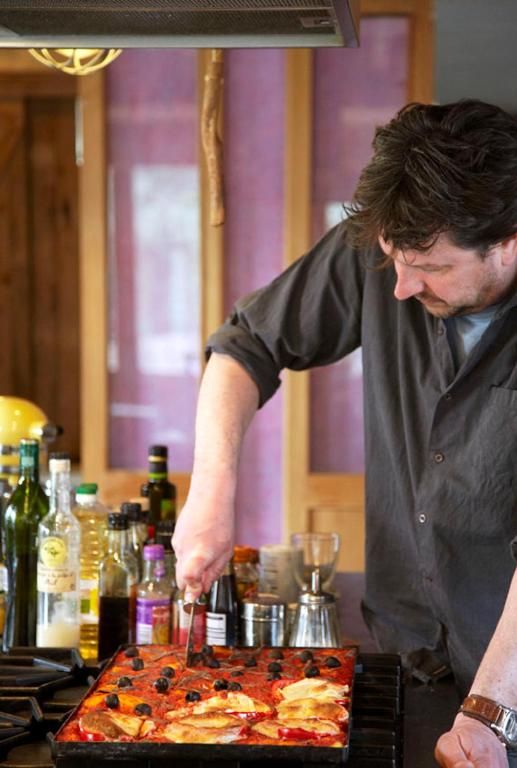 Der Gastgeber bereitet das Essen in der Kueche von In de Aap - Apartments & Guesthouse, Bergen, Nordholland, mit frischen Zutaten zu.