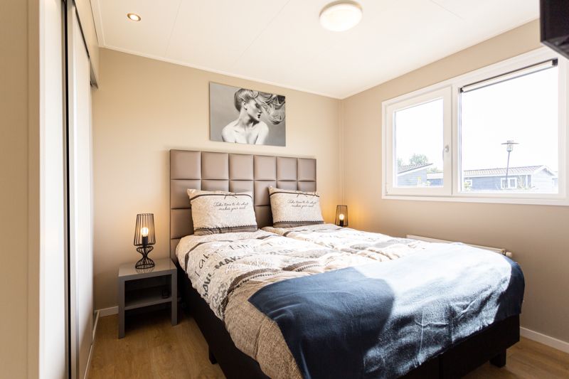 Cozy bedroom in Leijhoeve 4 persons Wellness, a vacation home in Beekbergen, Veluwe, with comfortable beds and natural light.