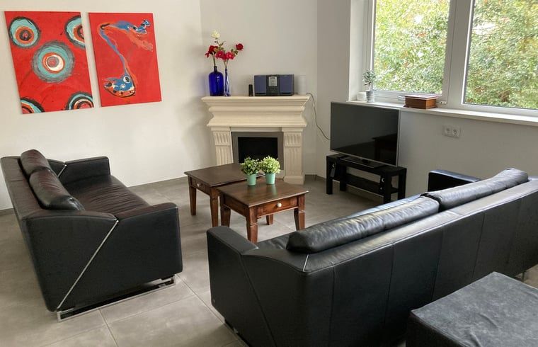 Gemuetliches Wohnzimmer des Ferienhauses in Beekbergen, Ferienhaus in der Region Veluwe in Gelderland, mit moderner Einrichtung und Blick auf die Natur.