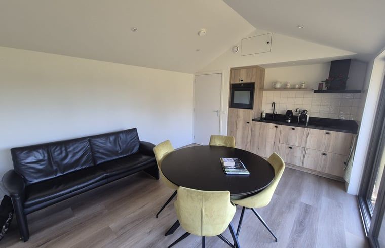 Gemuetlicher Innenbereich des Ferienhauses "Huisje in Harskamp", einem Ferienhaus in der Region Veluwe in Gelderland, mit moderner Kueche und komfortabler Sitzecke.