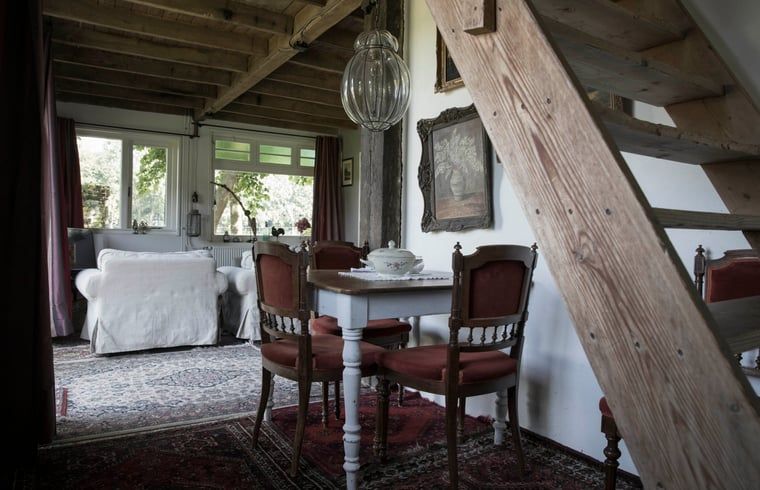 Gezellige binnenruimte van Huisje in Kootwijk, Veluwe, met houten interieur en eethoek.