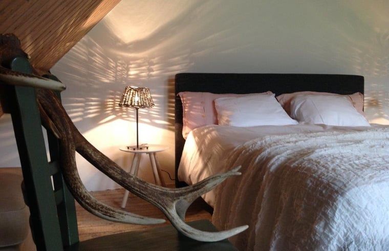 Sfeervolle slaapkamer in Huisje in Kootwijk, Veluwe, met comfortabel bed en rustieke details.