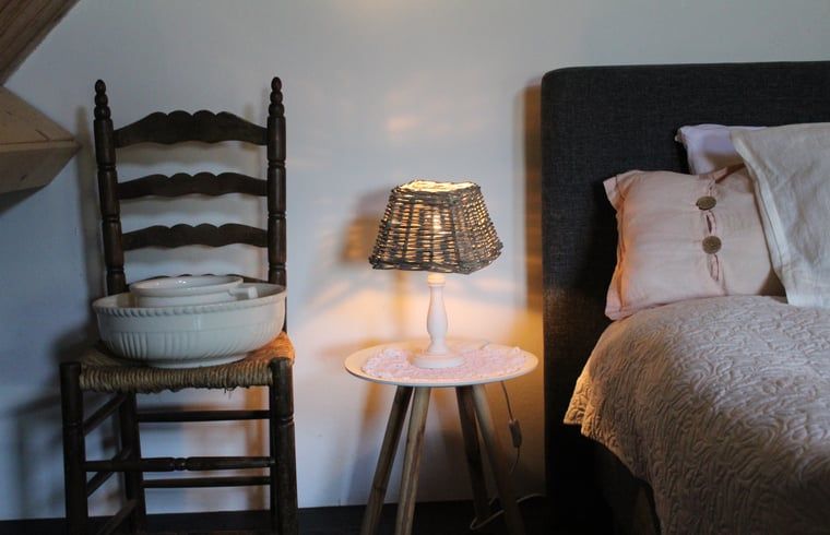 Rustieke slaapkamerhoek in Huisje in Kootwijk, Veluwe, met warme verlichting.