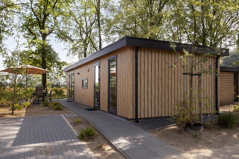 Module Wood 5 personen vakantiehuis in Ede Veluwe met houten gevel en terras in bosrijke omgeving.