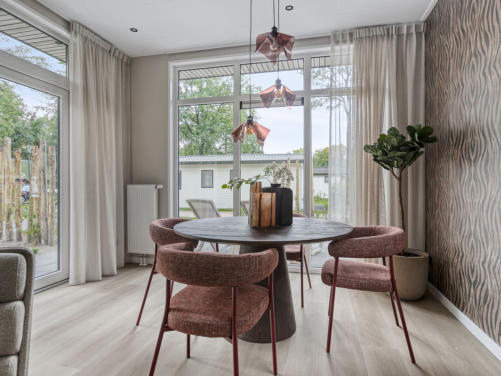 Essecke im Ferienhaus Wilgenhof, Ede, Veluwe, mit stimmungsvoller Beleuchtung und Blick auf den Garten.