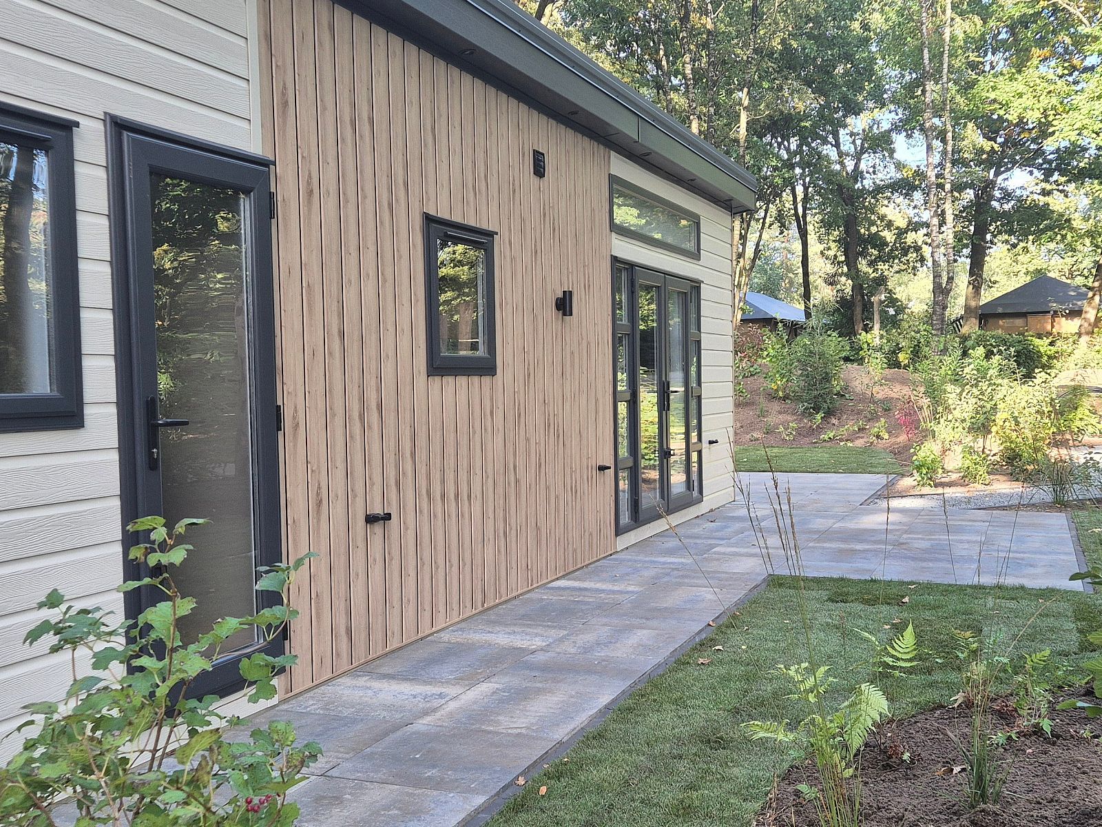 Seitenansicht des Ferienhauses Module Nova in Ede, Veluwe mit Terrasse und umliegender Natur.