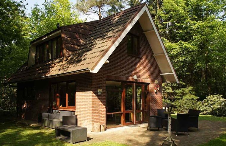 Vacation cottage in Emst with comfortable outdoor seating surrounded by green nature.