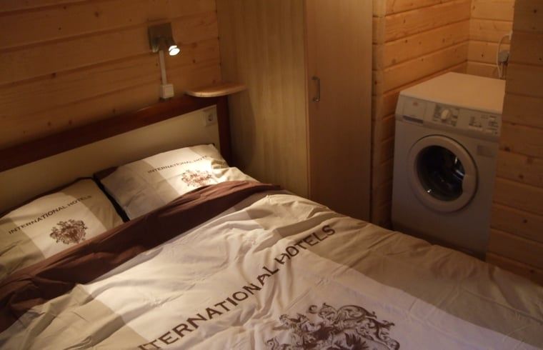 Schlafzimmer mit Doppelbett im Ferienhaus in Ermelo, Veluwe, inklusive Waschmaschine.