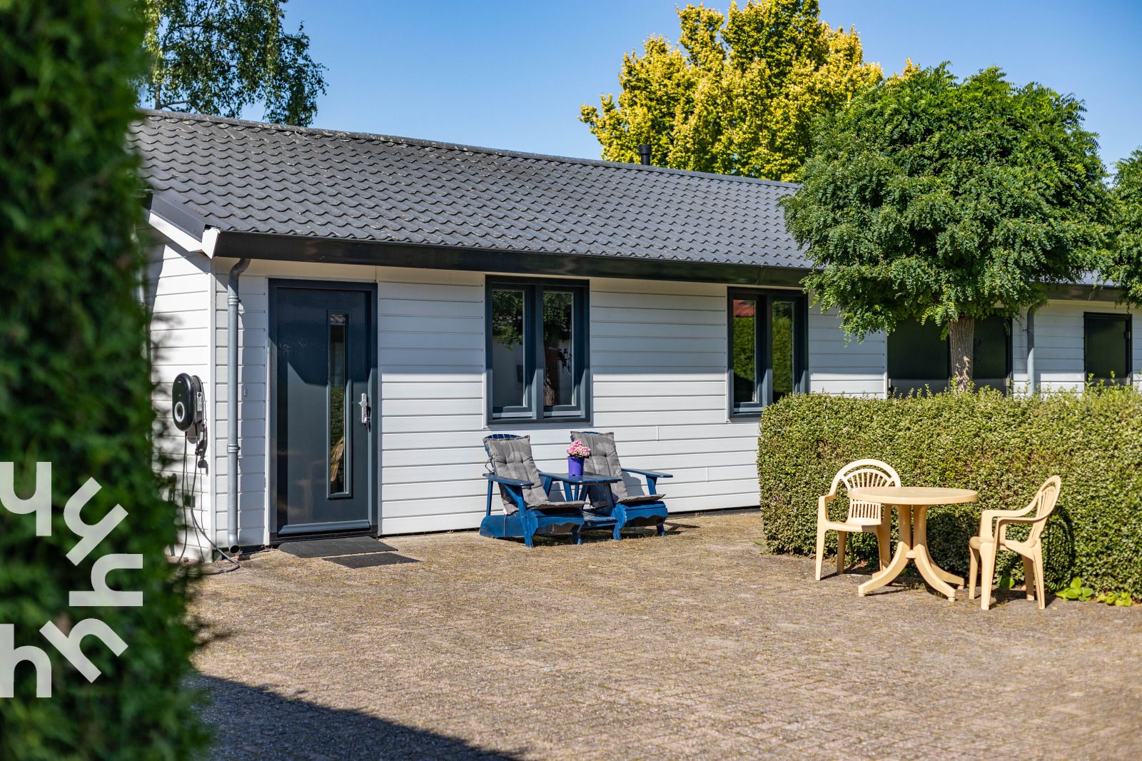 Vakantiehuis DG1560 in Ermelo, Veluwe, Gelderland met zonnig terras en comfortabele stoelen omgeven door groene natuur.