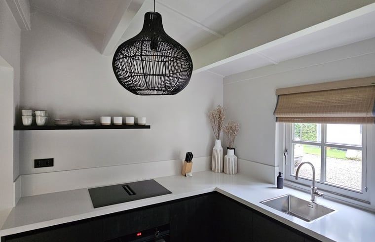 Stilvolle Kueche im Ferienhaus in Ermelo, Veluwe, Gelderland mit moderner Einrichtung und natuerlichem Licht durch das Fenster.