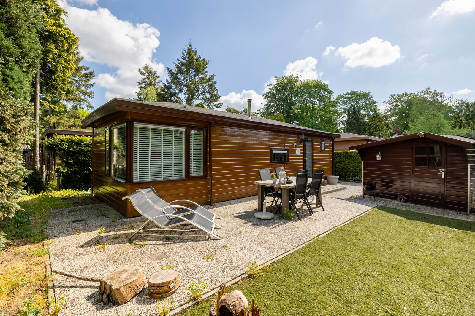 Gemuetliche Terrasse am Ferienhaus Tiny Lodge in Harderwijk, Veluwe, Gelderland mit Liegestuehlen und Esstisch.