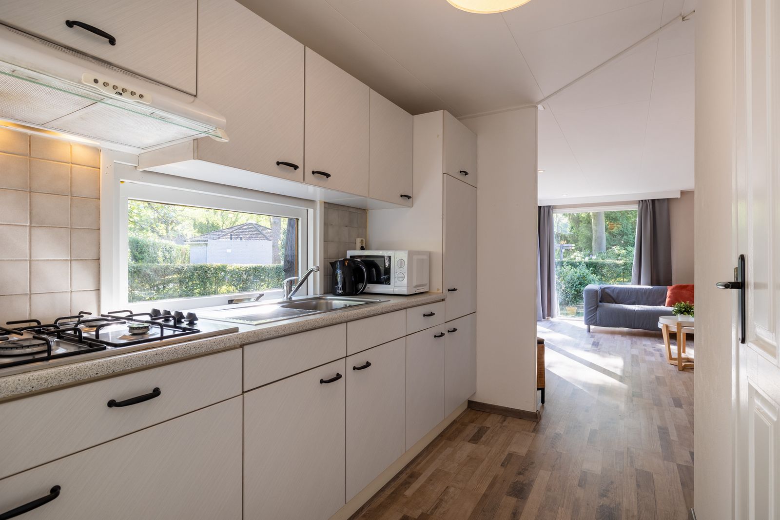 Moderne Kueche im Ferienhaus Tiny Lodge in Harderwijk, Veluwe, Gelderland mit Blick auf den Garten.