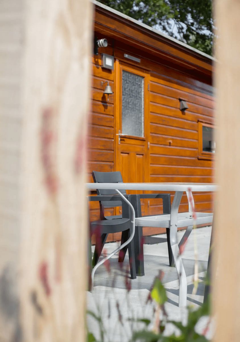 Aussenbereich der Tiny Lodge in Harderwijk, Veluwe, Gelderland mit Terrasse und Holzfassade.