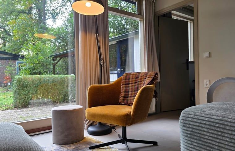 Gezellige binnenruimte van Vakantiehuis in Hoenderloo op de Veluwe, met comfortabele stoel en uitzicht op groene omgeving in Gelderland.