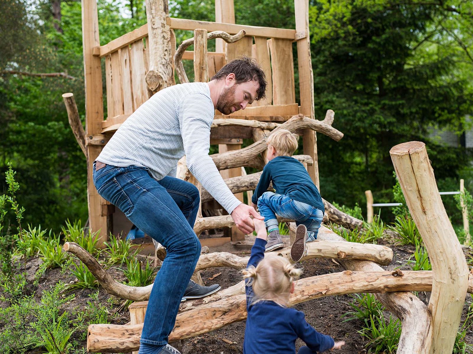 Children play on wooden playground equipment at detached house Hoenderloo, Veluwe, Gelderland.