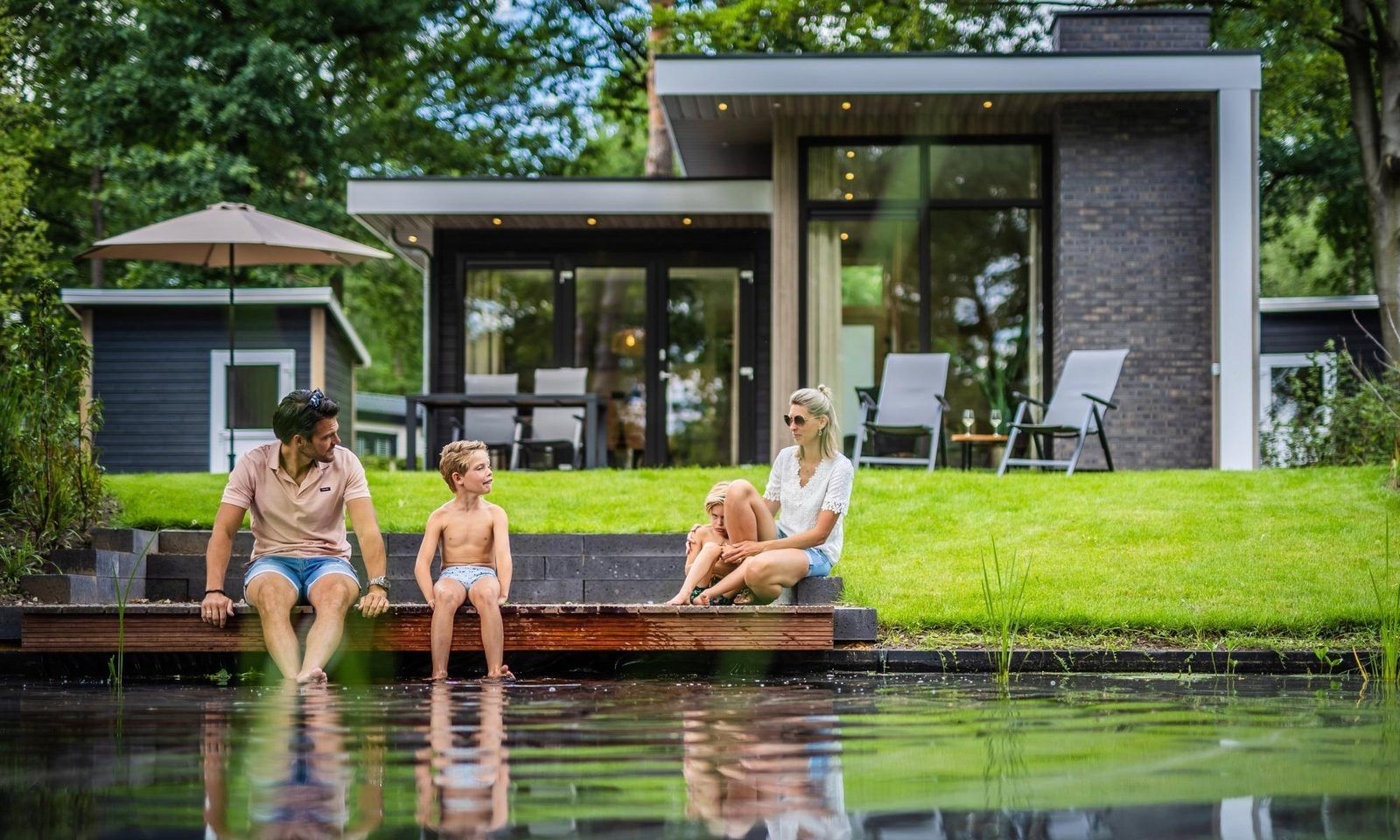Family enjoys the pond at Holiday home Deerhoeve comfort in Hoenderloo, Veluwe. Perfect for relaxation and nature.