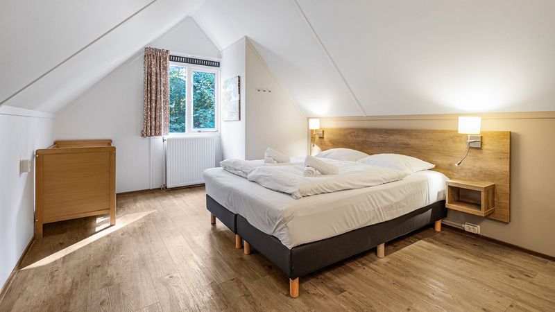 Ruime slaapkamer met tweepersoonsbed in Miggelenberg 8-persoons bungalow 8C, Hoenderloo, Veluwe.
