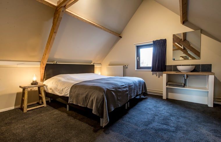 Sfeervolle slaapkamer in Huisje in Hoenderloo, Veluwe, met rustieke elementen.