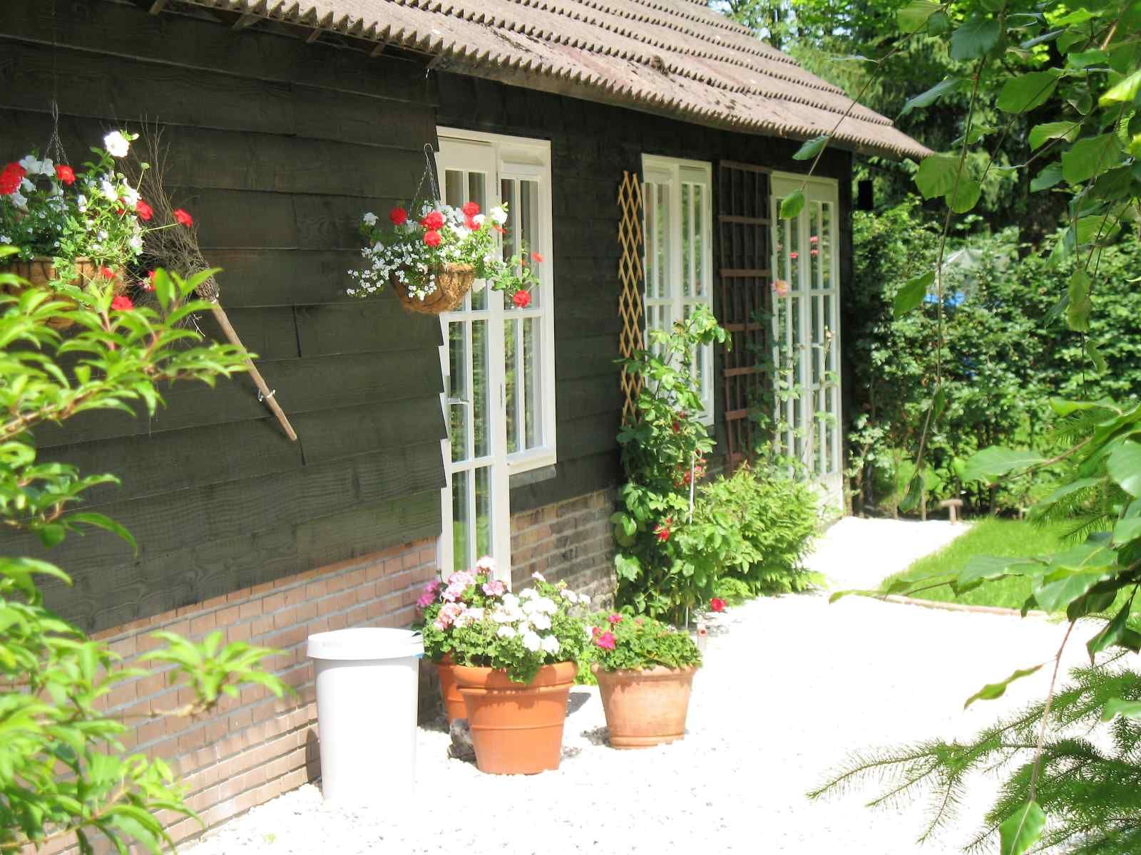Exterior of vacation home DG1276 in Putten, Veluwe, surrounded by flowers and greenery.