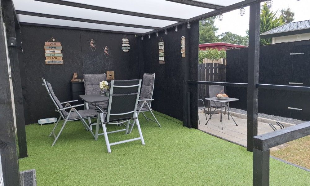 Covered porch of Chalet Relax in Putten, Veluwe, Gelderland, with comfortable seating area and views of the natural surroundings.
