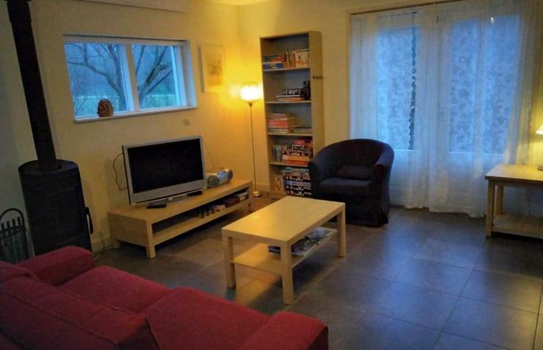 Gemuetliches Wohnzimmer im Ferienhaus in Putten, Veluwe, Gelderland mit komfortabler Sitzecke und Blick auf die natuerliche Umgebung.