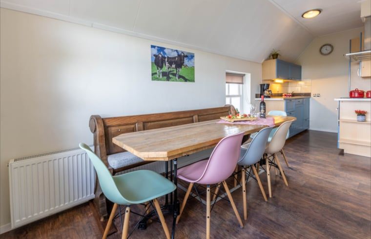 Dining area in Holiday Home in Wezep Oldebroek, Veluwe, Gelderland with spacious table and colorful chairs.