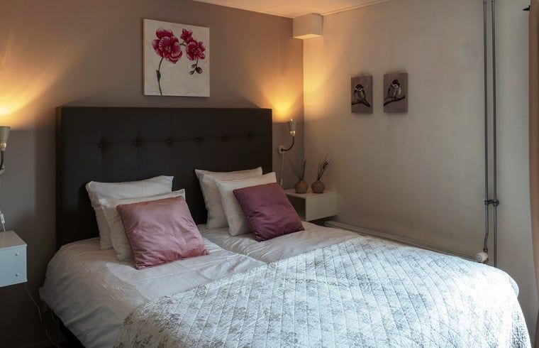 Sfeervolle slaapkamer met kunst aan de muur in Vakantiehuis in Voorthuizen Veluwe.