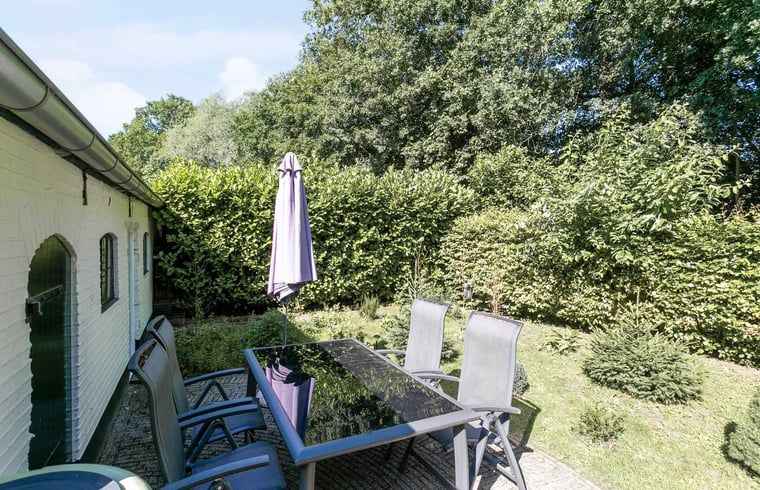 Esstisch mit Sonnenschirm im Garten des Ferienhauses in Vaassen, Veluwe, Gelderland.