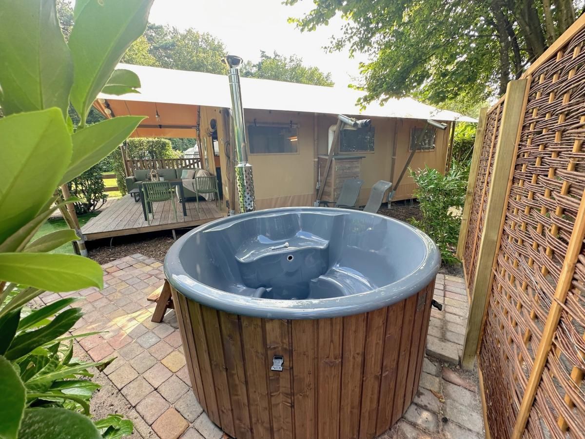 Geniet van luxe ontspanning bij tenthuis Libelle in Hulshorst, Veluwe, met een uitnodigende hot tub en ruime veranda in de natuur.